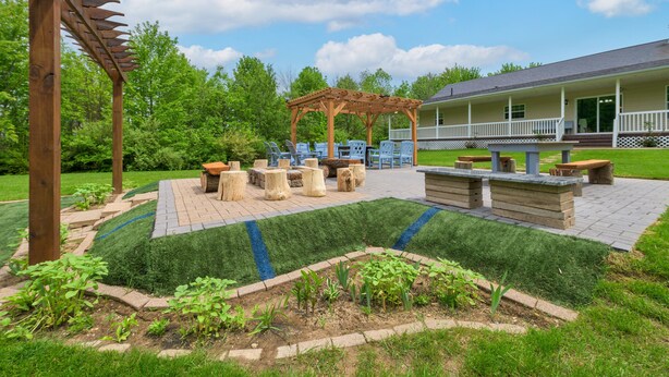 Eine Terrasse mit Sitzgelegenheiten im Freien, einer Pergola und einem Gebäude mit Veranda.