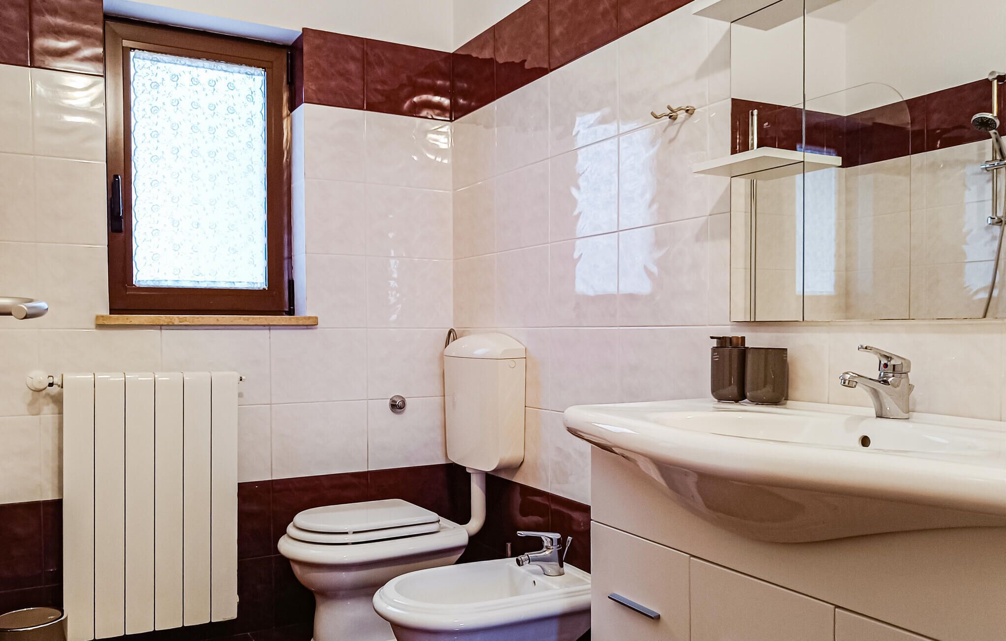 A bathroom with a toilet, sink, and a window.