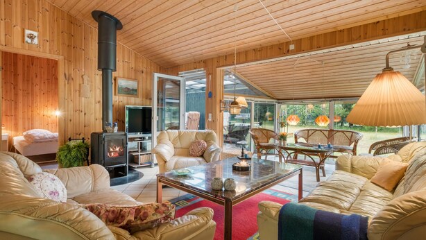 Ein gemütliches Blockhaus-Interieur mit Kamin, bequemen Sitzmöglichkeiten und einer Glastür zu einem Außenbereich.