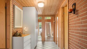Ein Flur mit Holzwänden und Fliesenboden, der zu einer Tür mit Glasfenster führt.