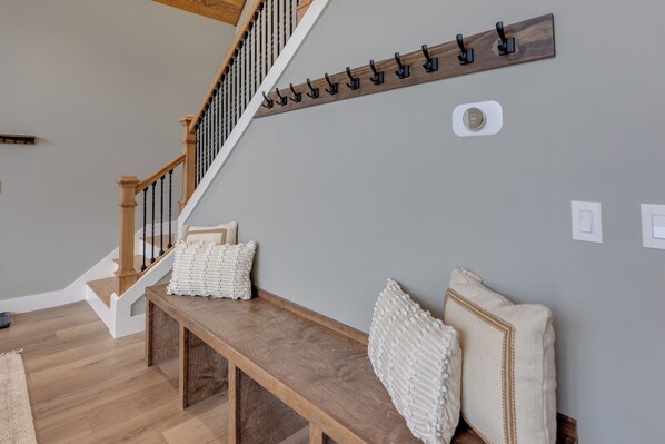 A staircase with wooden railings and a wall-mounted coat rack. - Brand new construction - Spacious Mountain Chalet in Sugar Hill, NH. Sleeps 18. (Sugar Hill)