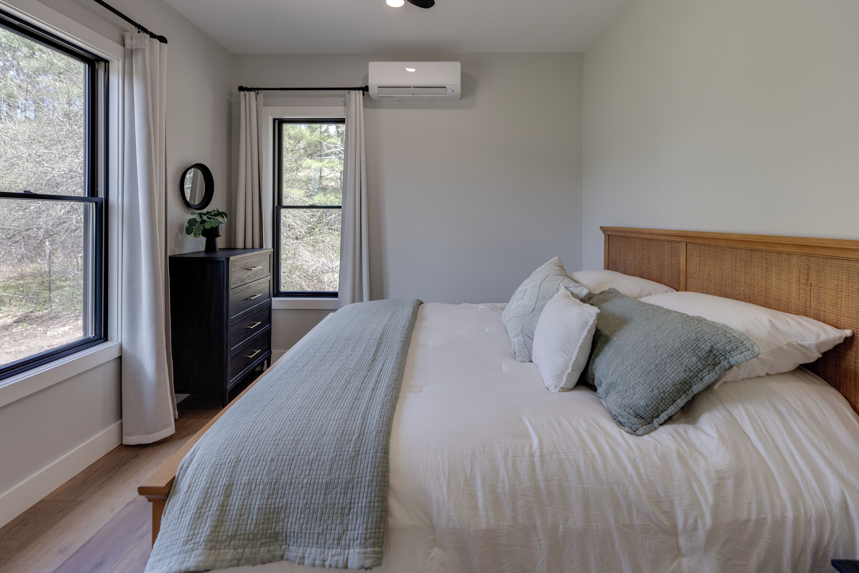 Un dormitorio con cama, cómoda, espejo y aire acondicionado.
