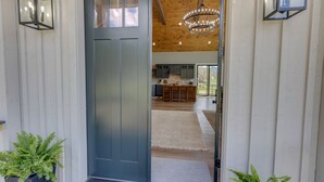 A modern entrance with a dark door, wooden ceiling, and potted plants.