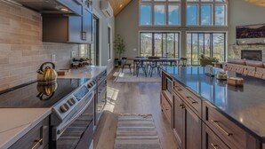 A spacious kitchen with a large island, wooden cabinets, and a stone fireplace.
