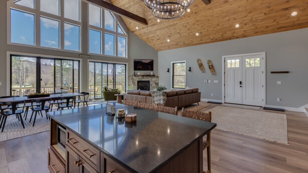 A spacious living area with a large island, a fireplace, and a view of the outdoors.