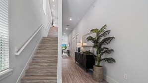 A modern interior with a staircase, a potted plant, and a console table. - Liberty Grandview: Private Pool, Water Park, Golf Views (Kissimmee)