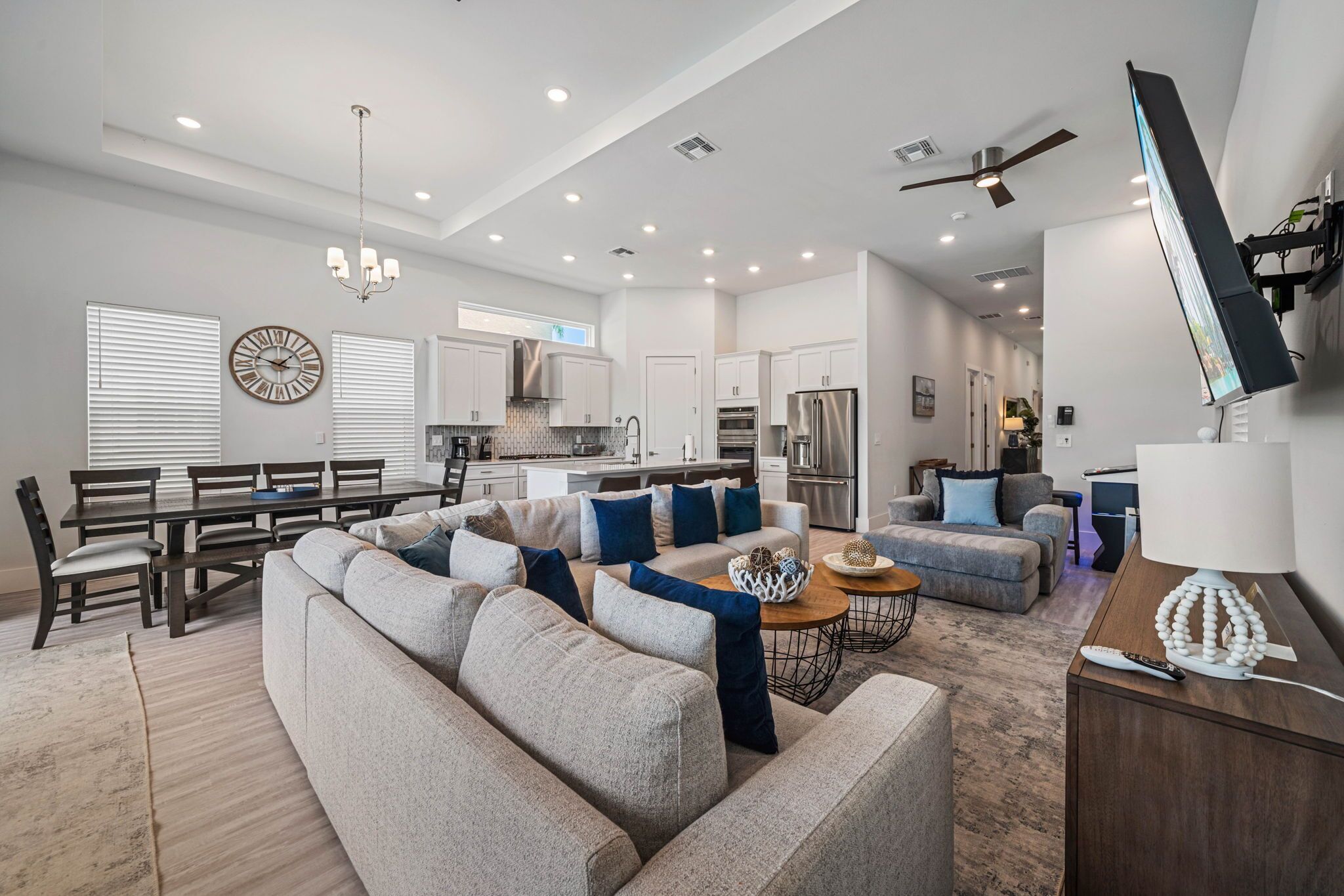 A spacious living room with a large sectional sofa, a dining area with a wooden table and chairs, and a kitchen with modern appliances.