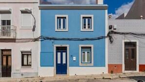 Ein zweistöckiges Gebäude mit blauer Fassade, weißem Zierdekor und einer blauen Tür.