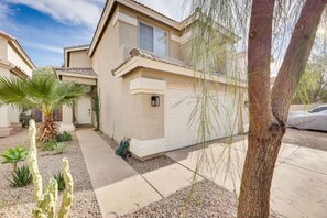 A residential building with a beige exterior, a covered driveway, and a small garden with cacti and a palm tree. - Mesa Oasis | Patio | Spacious | Central | Garage (Mesa)