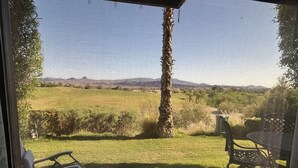 A patio with a view of a grassy field and mountains.