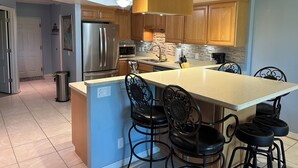 A modern kitchen with a central island, stainless steel appliances, and wooden cabinets.