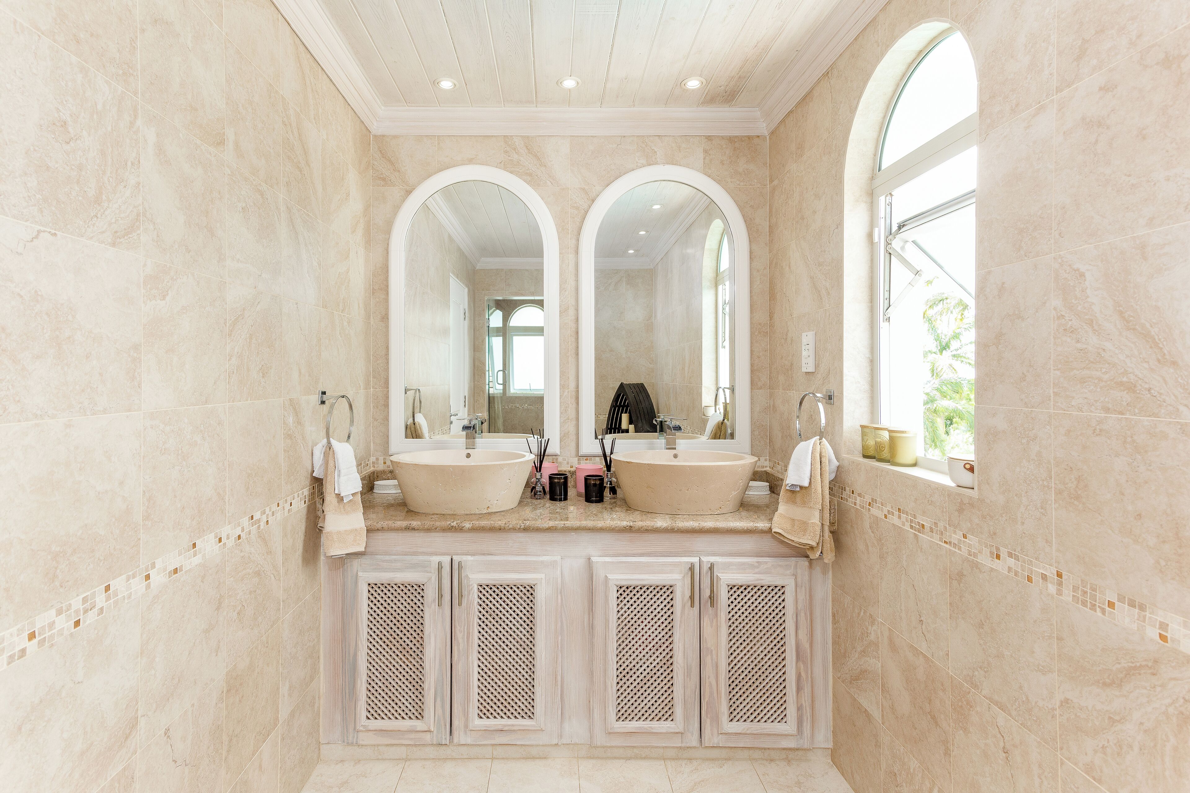 A bathroom with two sinks, large mirrors, and a window.