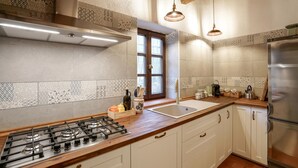 A modern kitchen with a gas stove, stainless steel appliances, and patterned tile backsplash.