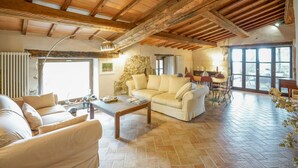 A spacious living area with a stone wall, a wooden ceiling, and a large window.