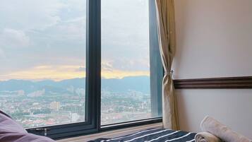 Une chambre d’hôtel dotée d’une grande fenêtre donnant sur le paysage urbain, d’un lit avec une literie à rayures et d’une serviette enroulée posée sur le lit.