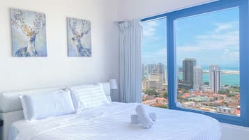 Relax in a stylish room with a large bed, wall art, and a panoramic city view.