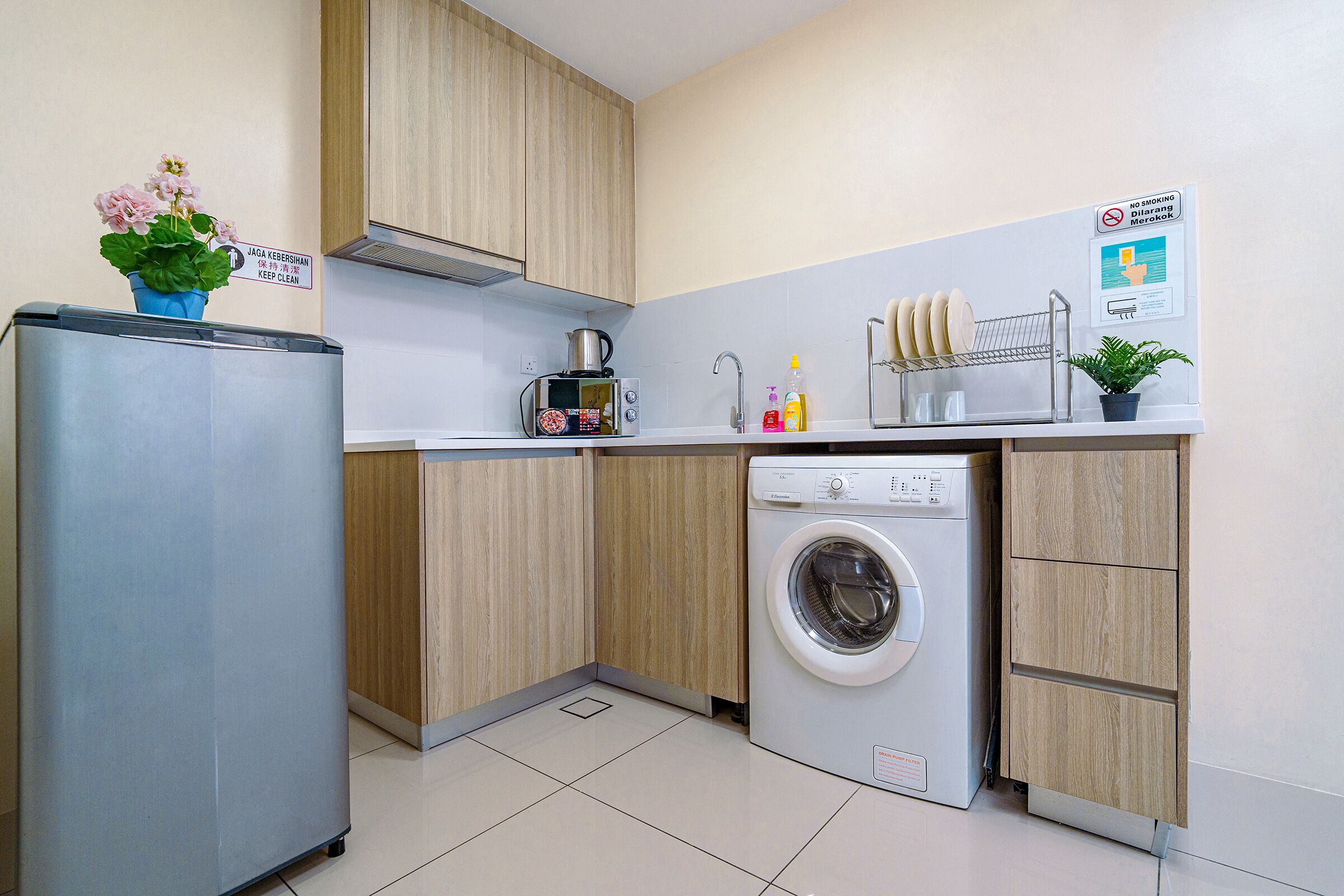 A compact kitchen with a refrigerator, microwave, sink, and washing machine.