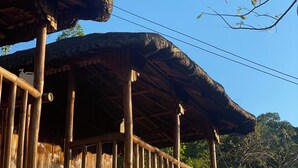 A rustic wooden structure with a thatched roof, bamboo railings, and a clear blue sky in the background. - Rustique Rue (Mabini)