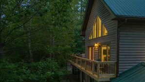 A log cabin with a deck, surrounded by dense forest. - Fels Haus- Hot Tub, WiFi, Gas Grill, located on Cliffview Resort (Campton)