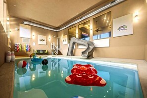 Une piscine intérieure au design moderne, dotée d’un robinet unique et de divers jouets pour la piscine.