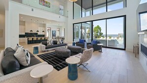 Een ruime woonkamer met een hoge plafond, moderne meubels en grote ramen met uitzicht op het omliggende landschap.