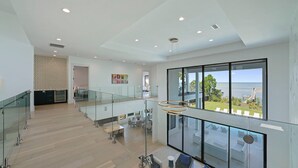 Ruime inrichting met een balkon dat uitkijkt over een prachtig uitzicht, moderne meubels en een wand met een geometrisch patroon.