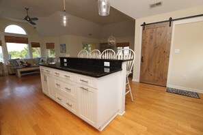 Eine geräumige Küche mit einer großen Kochinsel, weißen Schränken und einer schwarzen Arbeitsplatte.