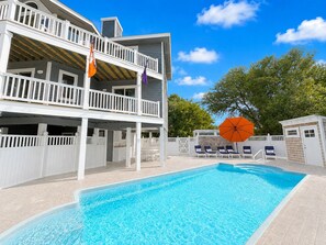 A two-story building with a swimming pool, outdoor seating, and a fenced deck area.