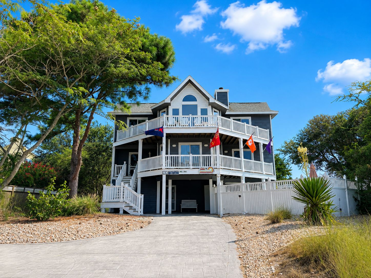 A two-story house with a balcony, a driveway, and a flag in front.
