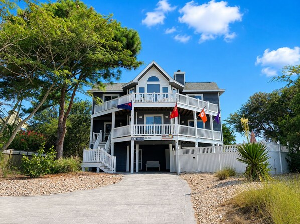 A two-story house with a balcony, a driveway, and a flag in front.
