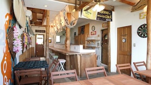 Un rústico área de bar con muebles de madera, un dardo y un letrero que dice 