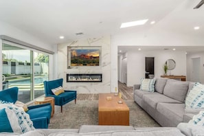 Una sala de estar moderna con chimenea, un sofá, un sillón azul y una mesa de centro.