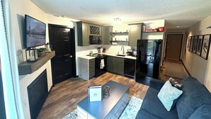Eine moderne Küche mit eingebauter Mikrowelle, Backofen und Kühlschrank. Ein Essbereich mit Sofa und Couchtisch vorhanden.