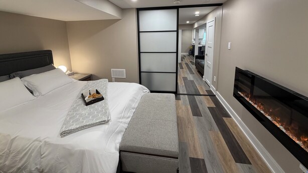 Ein modernes Hotelzimmer mit Bett, Nachttisch, Lampe und Kamin.