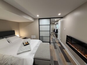 Ein modernes Hotelzimmer mit Bett, Nachttisch, Lampe und Kamin.