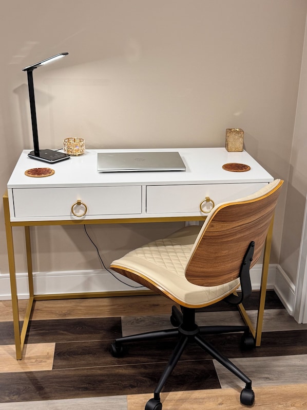 Un escritorio blanco con una laptop, una lámpara y objetos decorativos.