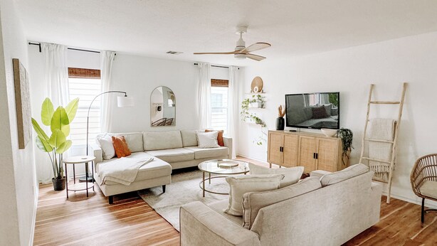 Ein Wohnzimmer mit Ecksofa, Couchtisch, Fernseher und Deckenventilator.