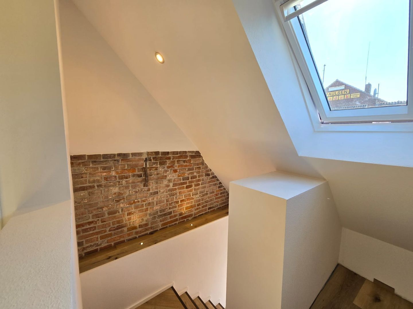 Una camera in stile loft con mattoni a vista, soffitto inclinato e finestra a lucernario.