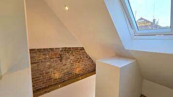 Una camera in stile loft con mattoni a vista, soffitto inclinato e finestra a lucernario.
