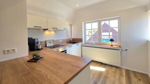Een moderne keuken met een houten aanrecht, witte kastjes, een raam met uitzicht en een ingebouwde kookplaat.