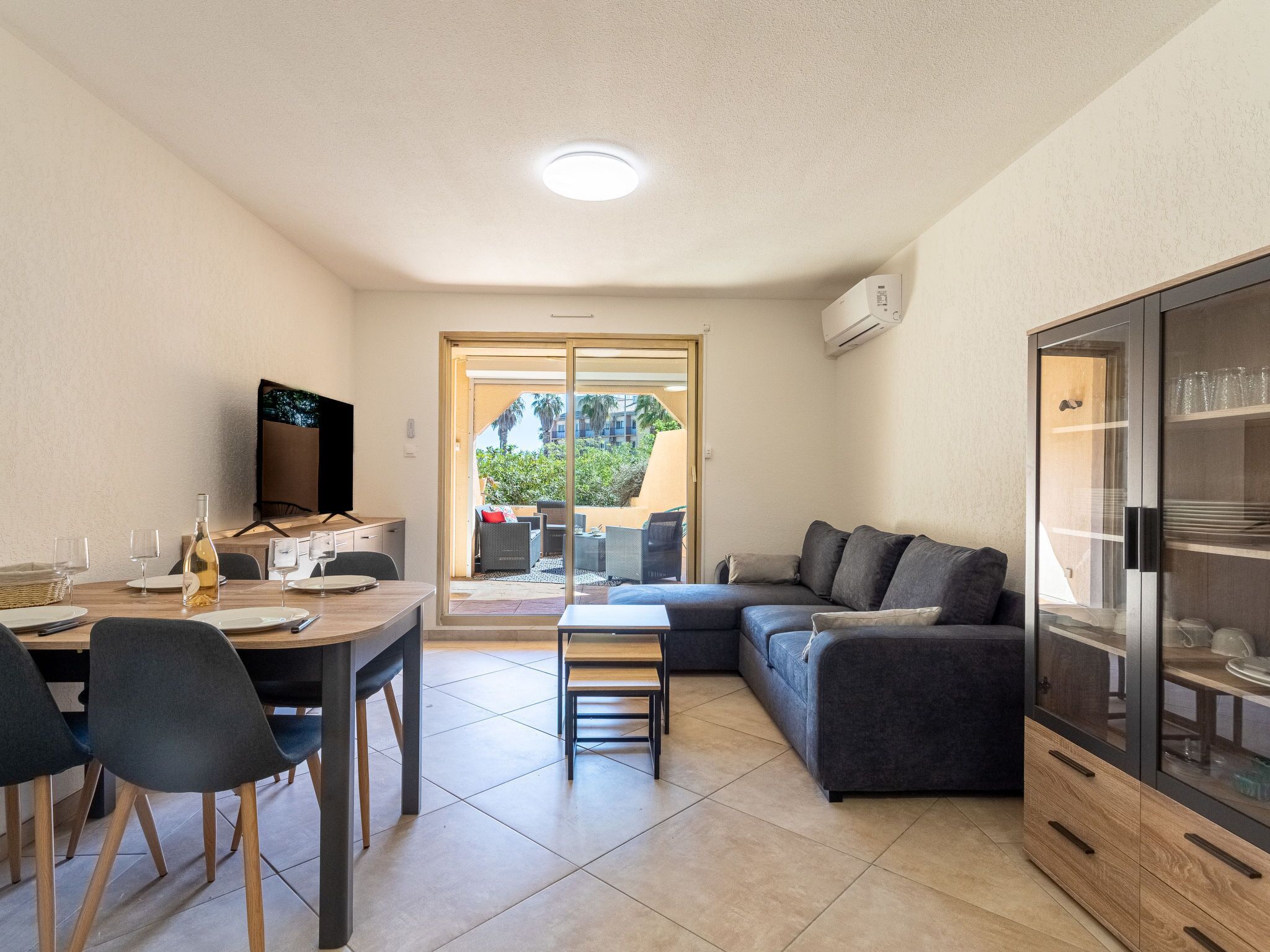 A compact living space with a dining area, a sofa, a TV, and a glass cabinet.