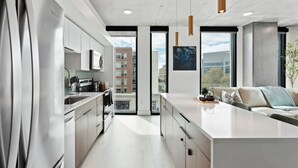 A modern kitchen with a large island, stainless steel appliances, and a view of the city through large windows. - 2bd/2ba Best style and location/Pool+spa/gym/pkg! (Salt Lake City)