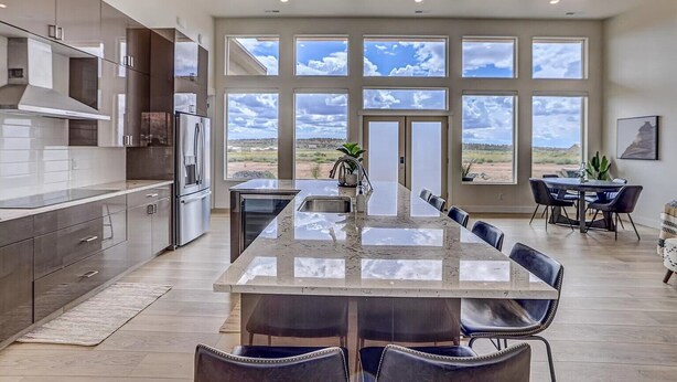 A modern kitchen with a large island, ample natural light from large windows, and a view of the outdoors.