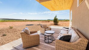 A covered outdoor seating area with wicker furniture and a view of the landscape.