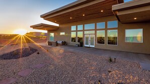 A modern building with a flat roof, large windows, and a gravel driveway.