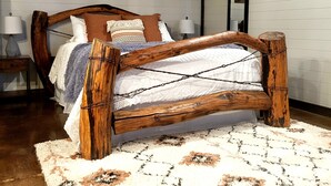 A rustic bedroom with a wooden bed frame, a fluffy white rug, and a painting of a bull on the wall.