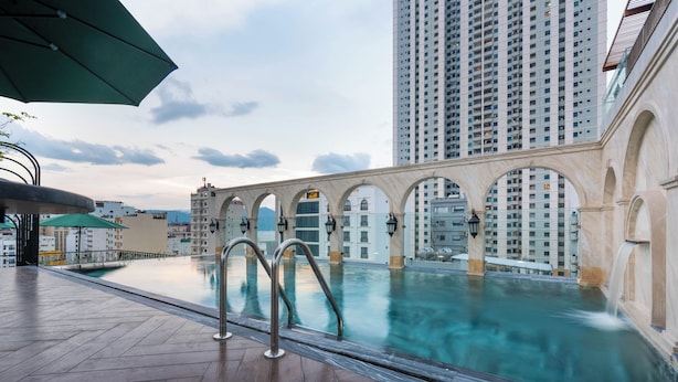 Piscina no terraço com passarelas em arco e vista para edifícios altos.