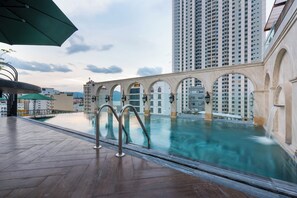 A rooftop swimming pool with arched walkways and a view of high-rise buildings. - Louis Mo Apartment (Da Nang)