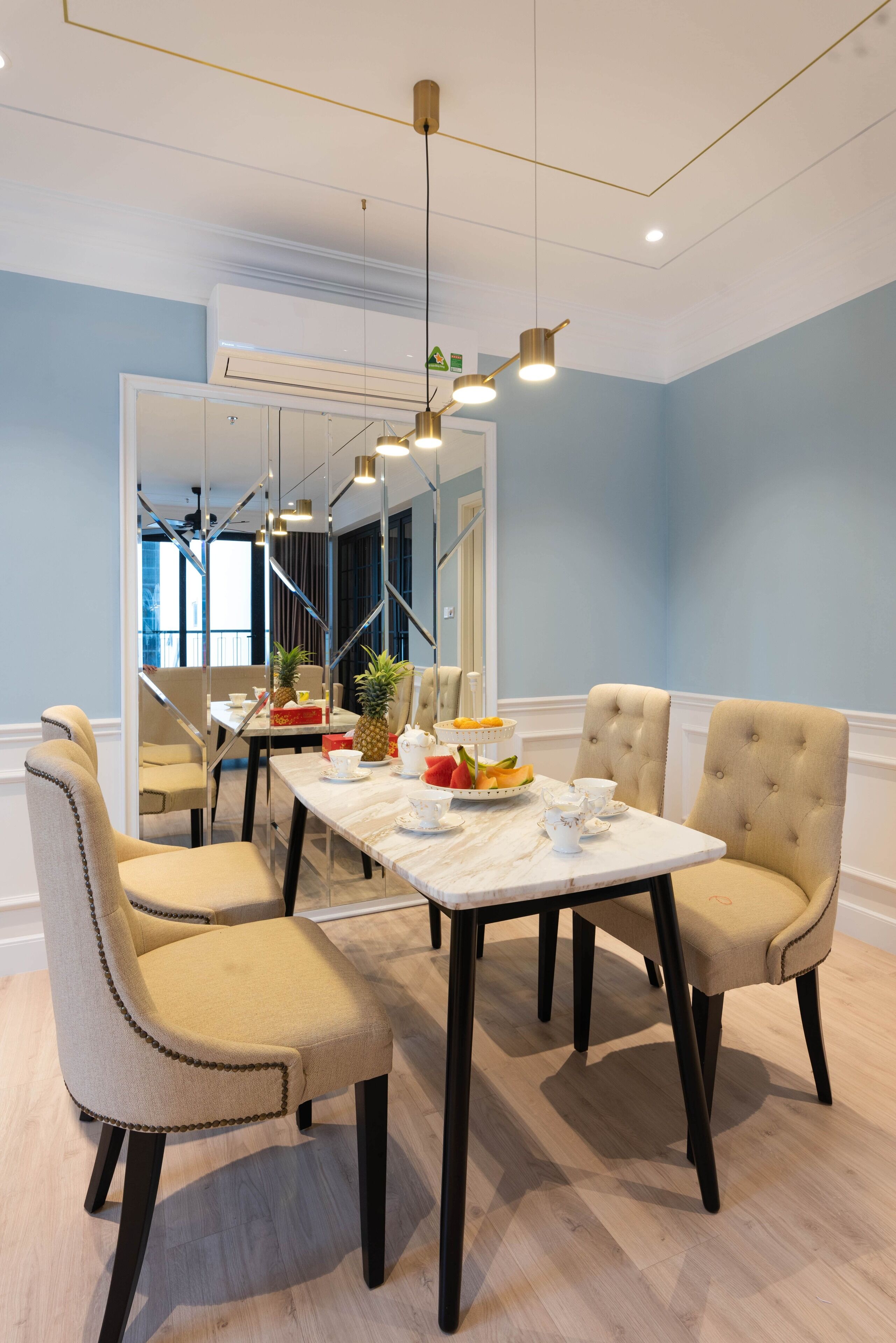 A dining area with a marble table, four upholstered chairs, and a chandelier.
