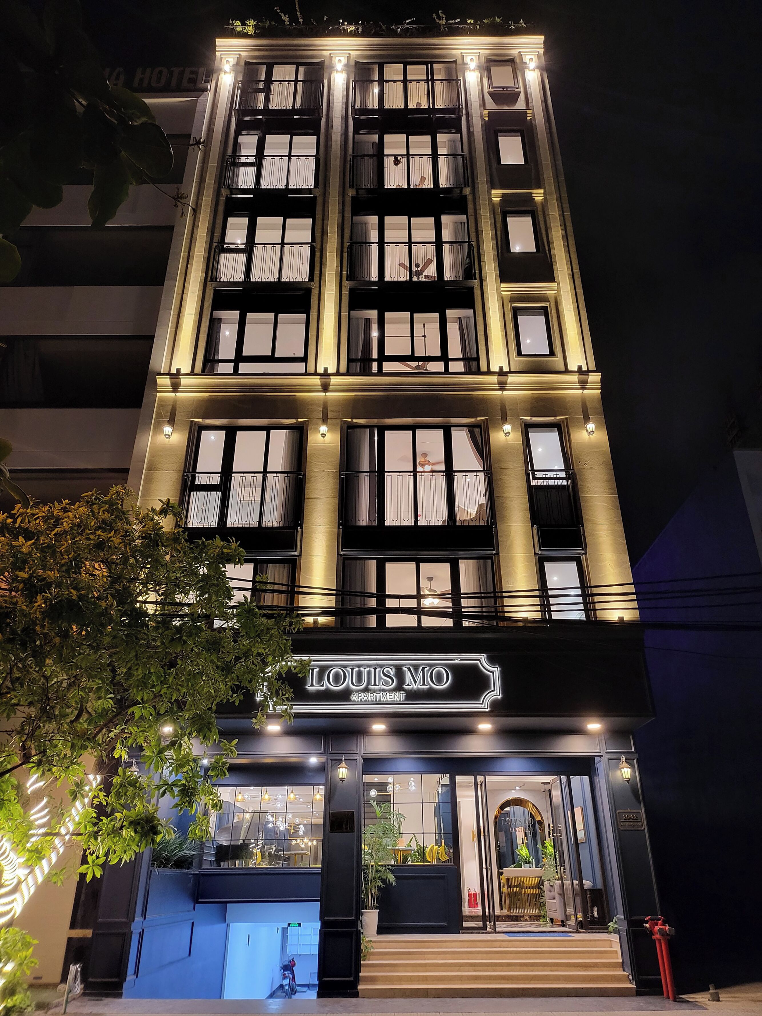A multi-story building with illuminated signage reading "LOUIS MO APARTMENT."